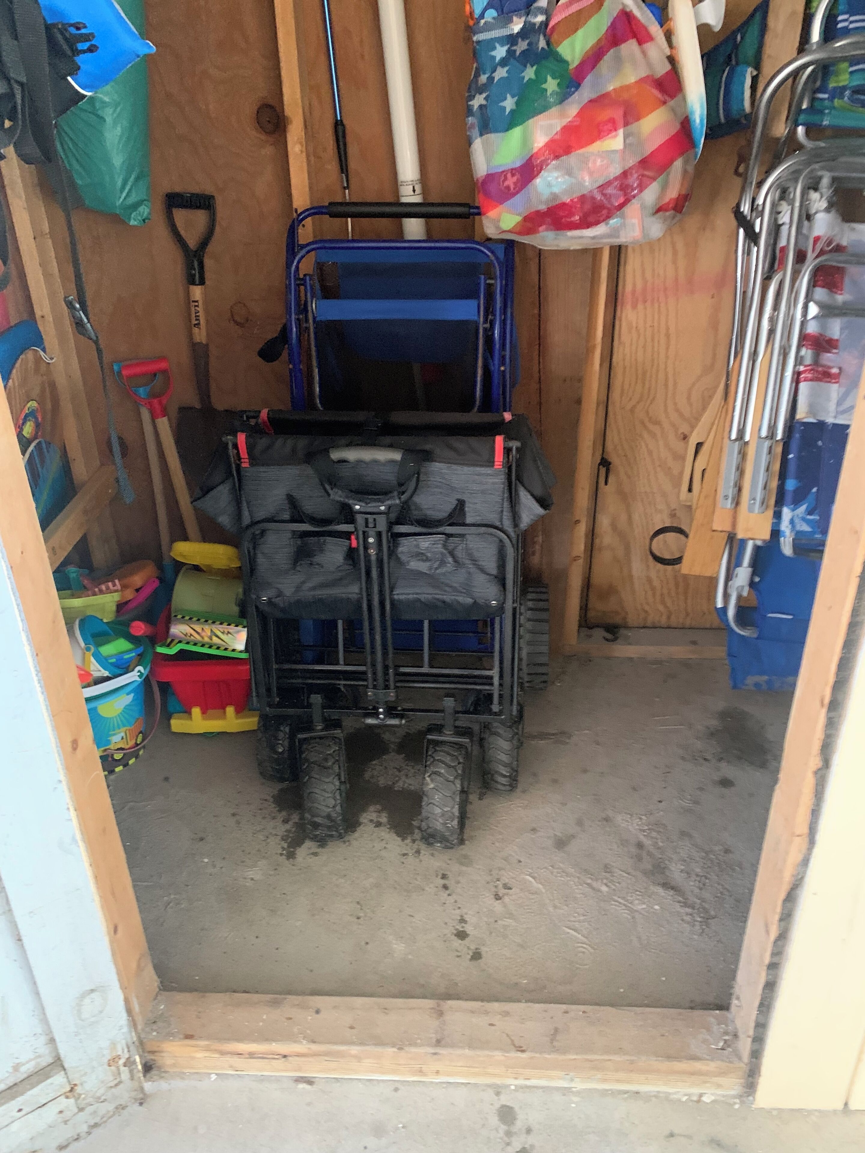 A small storage room with a blue cart and a red shovel.