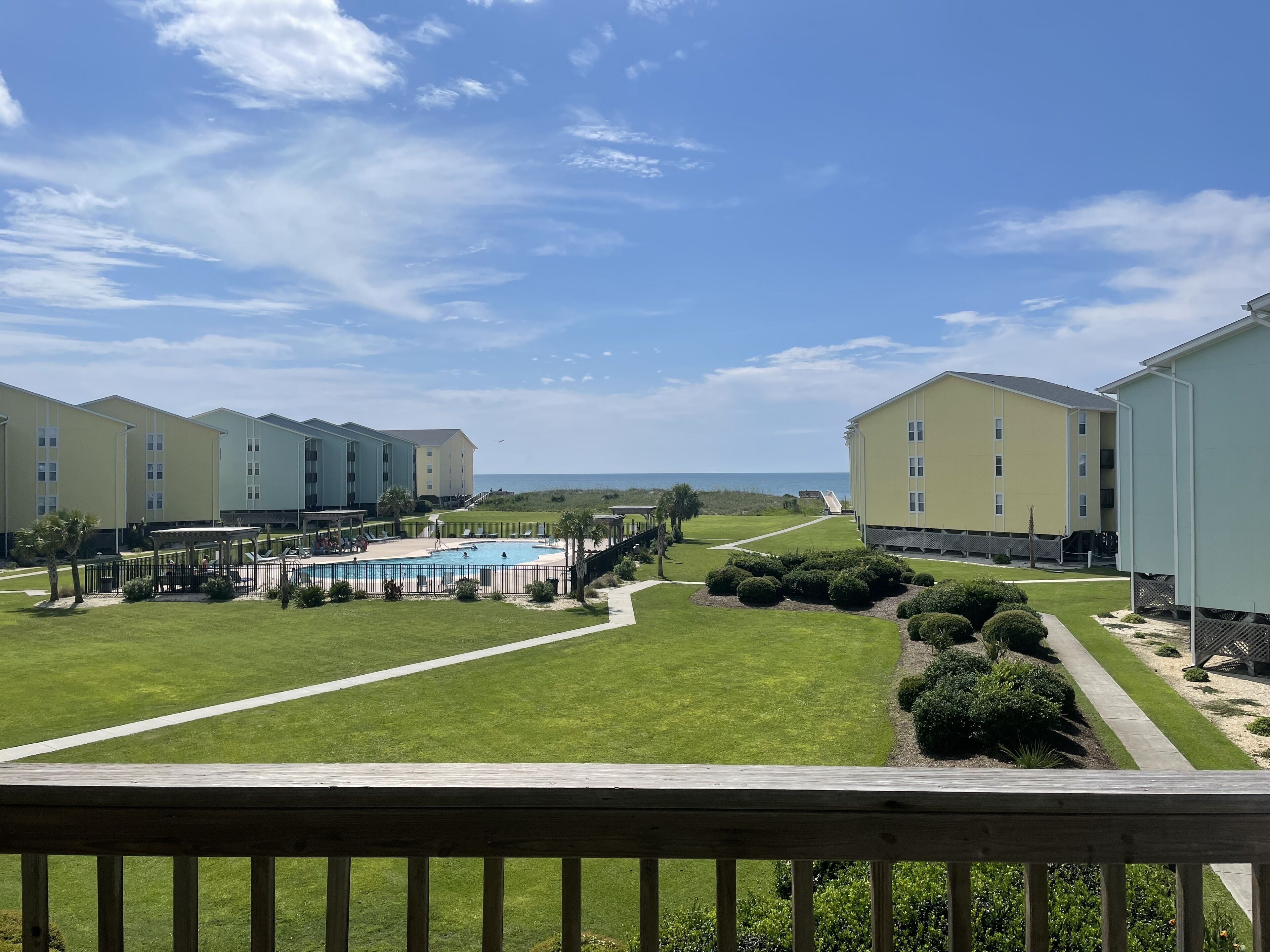A resort with multiple buildings, a pool area, and a clear view of the ocean.