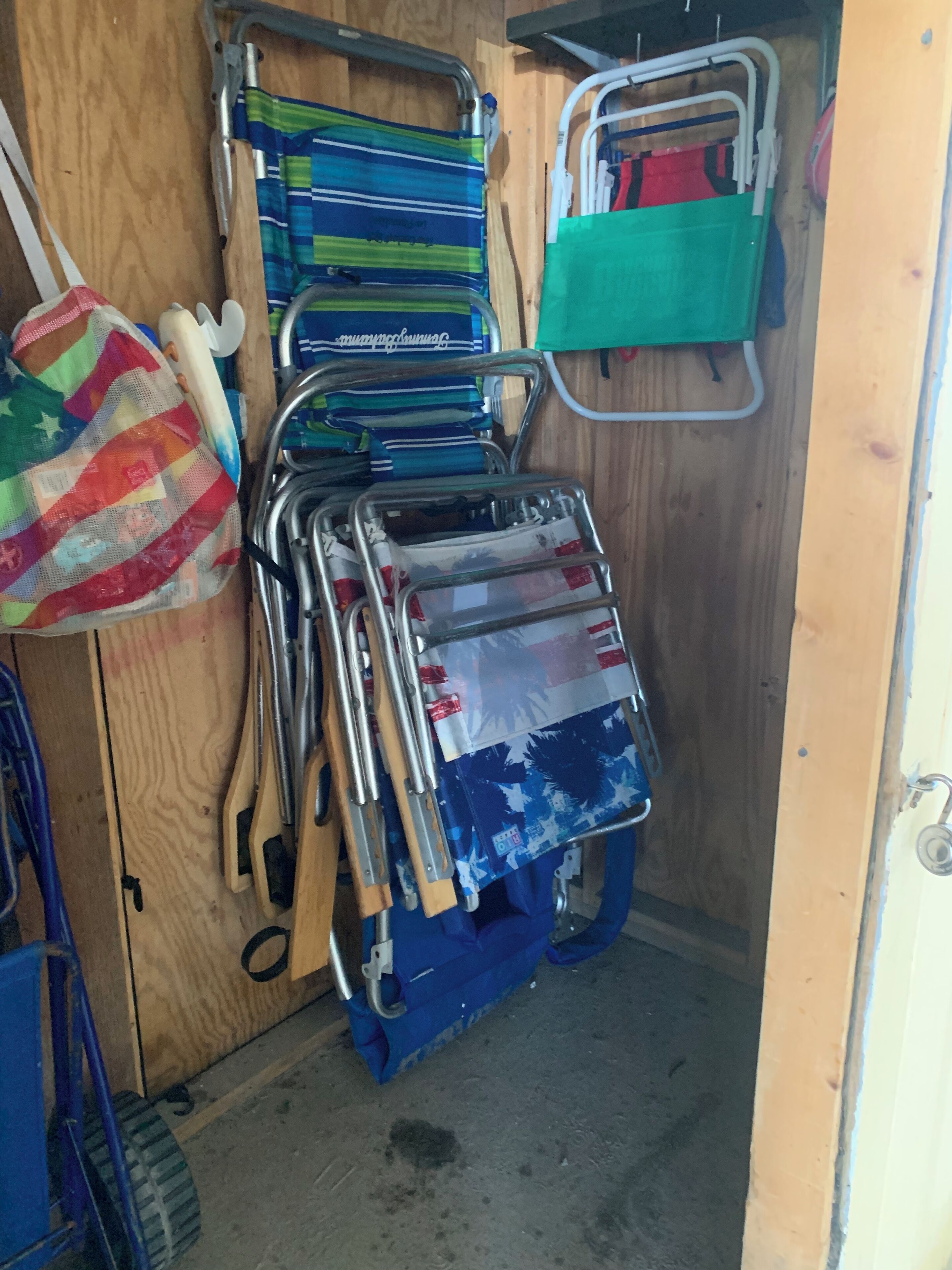 A storage area with metal racks holding various items, including folded clothes and bags.