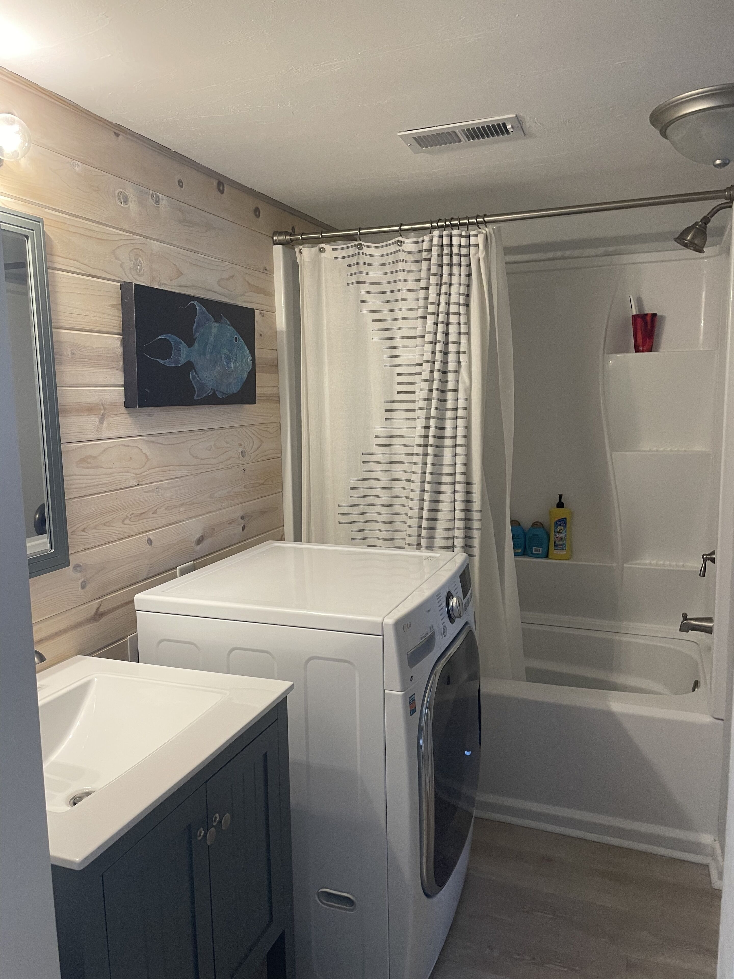 A compact bathroom with a washing machine, a bathtub, and a shower.