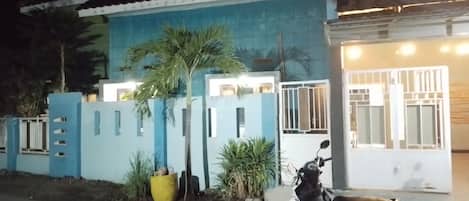 A residential building with a blue exterior, a gated entrance, and a parked scooter.
