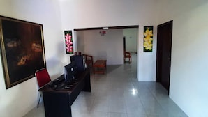 A hallway with a desk, chairs, and artwork on the walls. - 999 KHS Homestay (Banyuwangi)