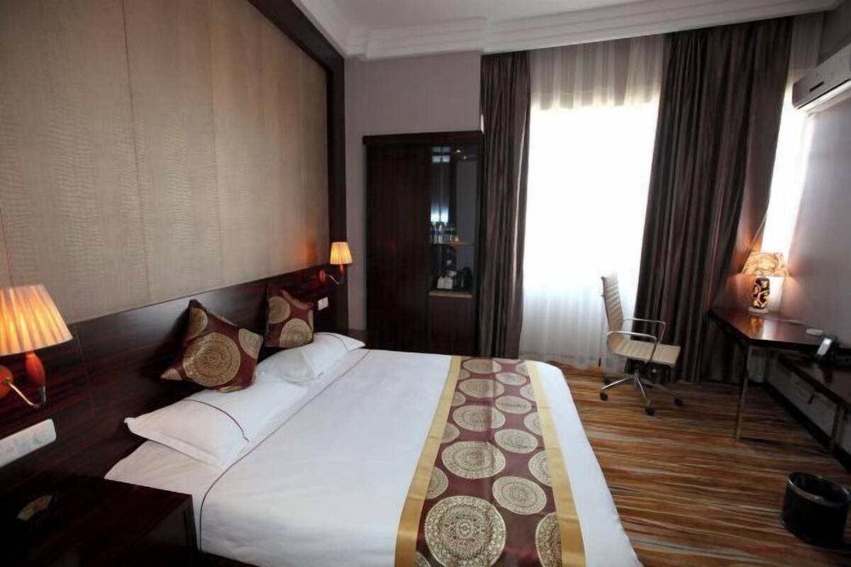 A hotel room with a large bed, bedside tables, a desk, and a chair.