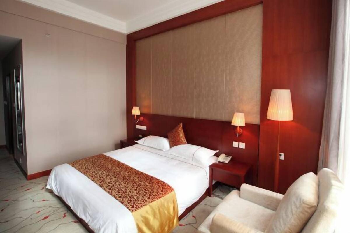 A hotel room with a large bed, bedside lamps, a desk, and a chair.