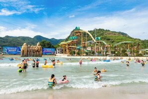 Una playa con toboganes acuáticos y montañas al fondo.