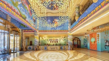 A lobby with a central reception desk, a large circular floor design, and a ceiling with a fish mural.