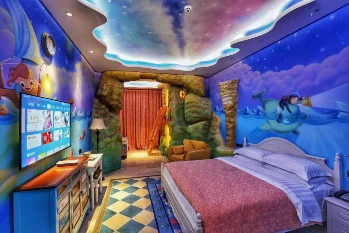 Ein Zimmer mit einem Bett, einem Fernseher, einem Schreibtisch und einem Wandbild.