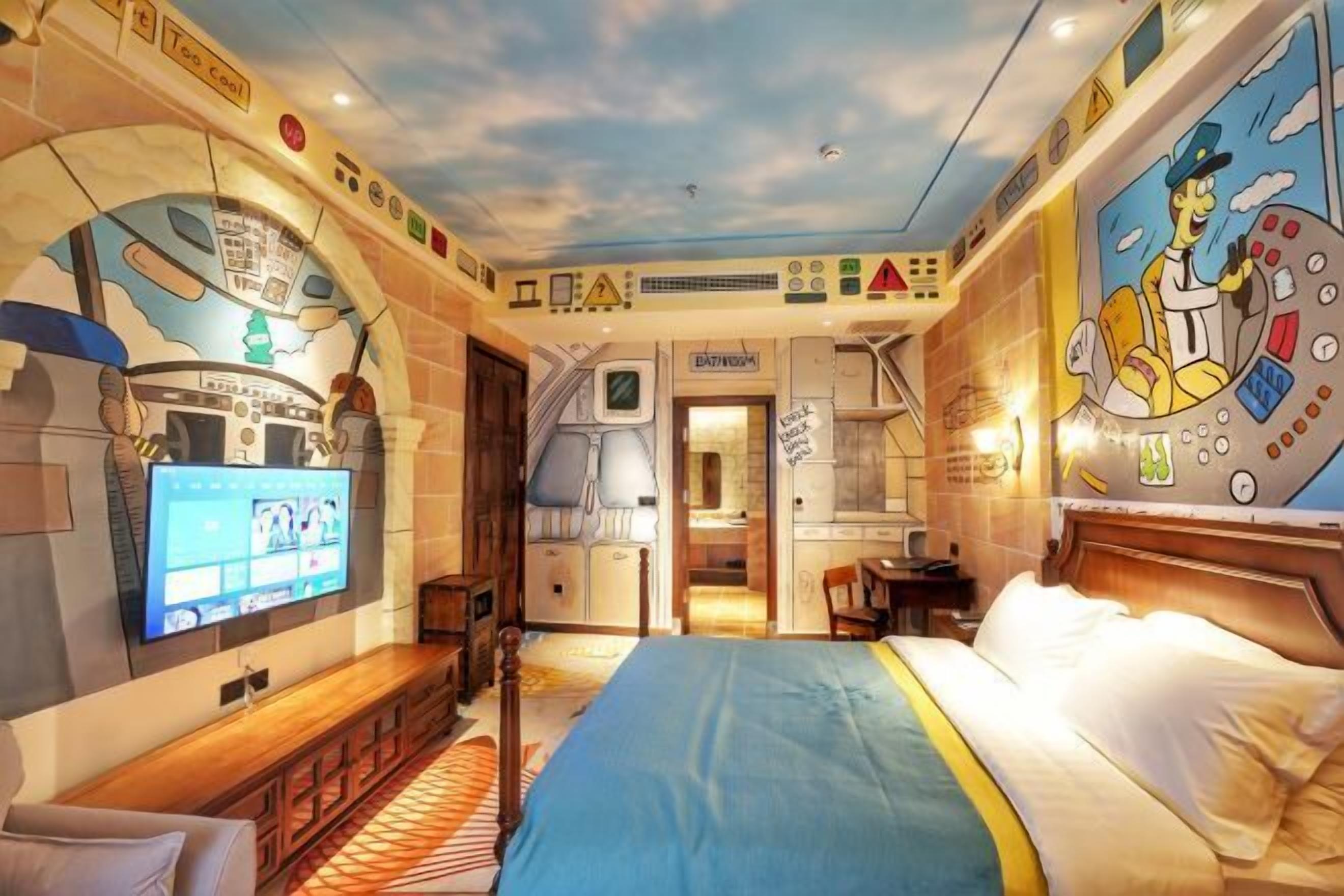 A room with a bed, a TV, a desk, and a bathroom.
