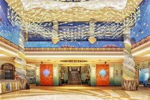 Eine prachtvolle Lobby mit einer zentralen Treppe, einer verzierten Decke und dekorativen Säulen.