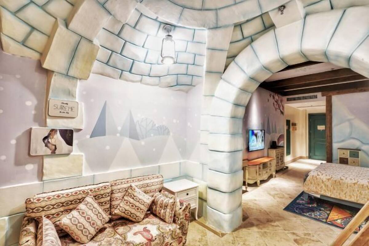 Ein Zimmer mit steinernen Rundbogen, einem Bett mit gemusterten Betttextilien, einem Fernseher und einem kleinen Tisch mit Stuhl.
