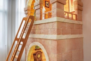 Ein Steinbau mit Rundbogenöffnungen und einem hölzernen Stuhl davor.