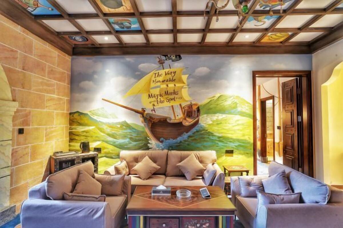 Ein Zimmer mit Wandgemälde eines Segelschiffs, einer Sofagarnitur und einem Couchtisch.
