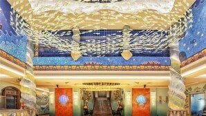 Un hall d’entrée spacieux, agrémenté d’un magnifique escalier, de colonnes richement décorées et d’un plafond orné de motifs de poissons.