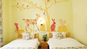 Una habitació amb dos llits, un mural al mur amb un arbre i animals, i una taula petita amb una planta.