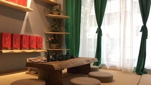 Habitació amb taula de fusta, otomans rodons, prestatges amb plantes en test i bosses de regal vermelles.