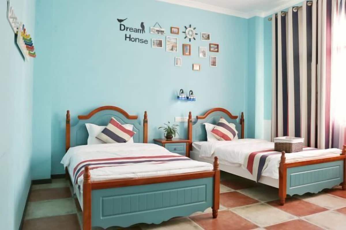 A room with two wooden beds, a wall with framed pictures, and a striped curtain.