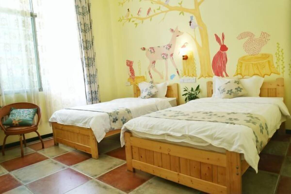 A room with two wooden beds, a chair, and a wall mural.