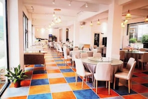 A hotel dining area with round tables and chairs, a colorful checkered floor, and large windows. - Danxia Firefly Boutique Inn (Renhua)