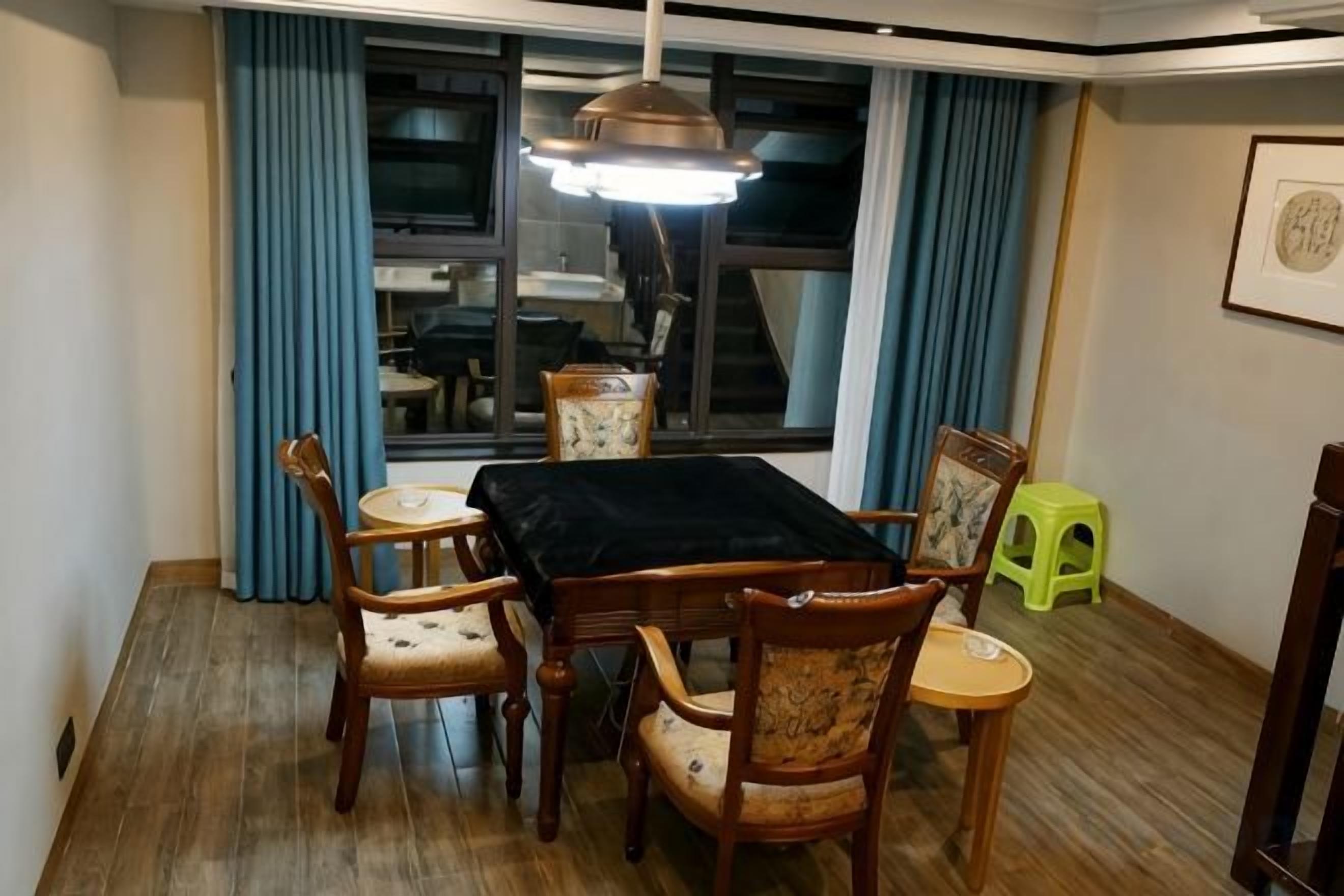 Un comedor con una mesa y sillas, un ventanal con cortinas y una lámpara colgante.