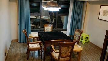 Un comedor con una mesa y sillas, un ventanal con cortinas y una lámpara colgante.
