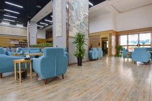 A spacious indoor area with seating arrangements, a large vertical artwork, and a view through the windows. - Lanting Culture Theme Hotel (Yingshan)