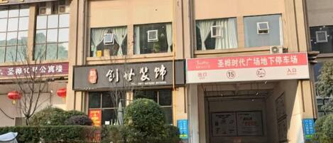 A building with multiple signs, including one for a car wash and another for a business. There are bicycles parked in front and a person walking.