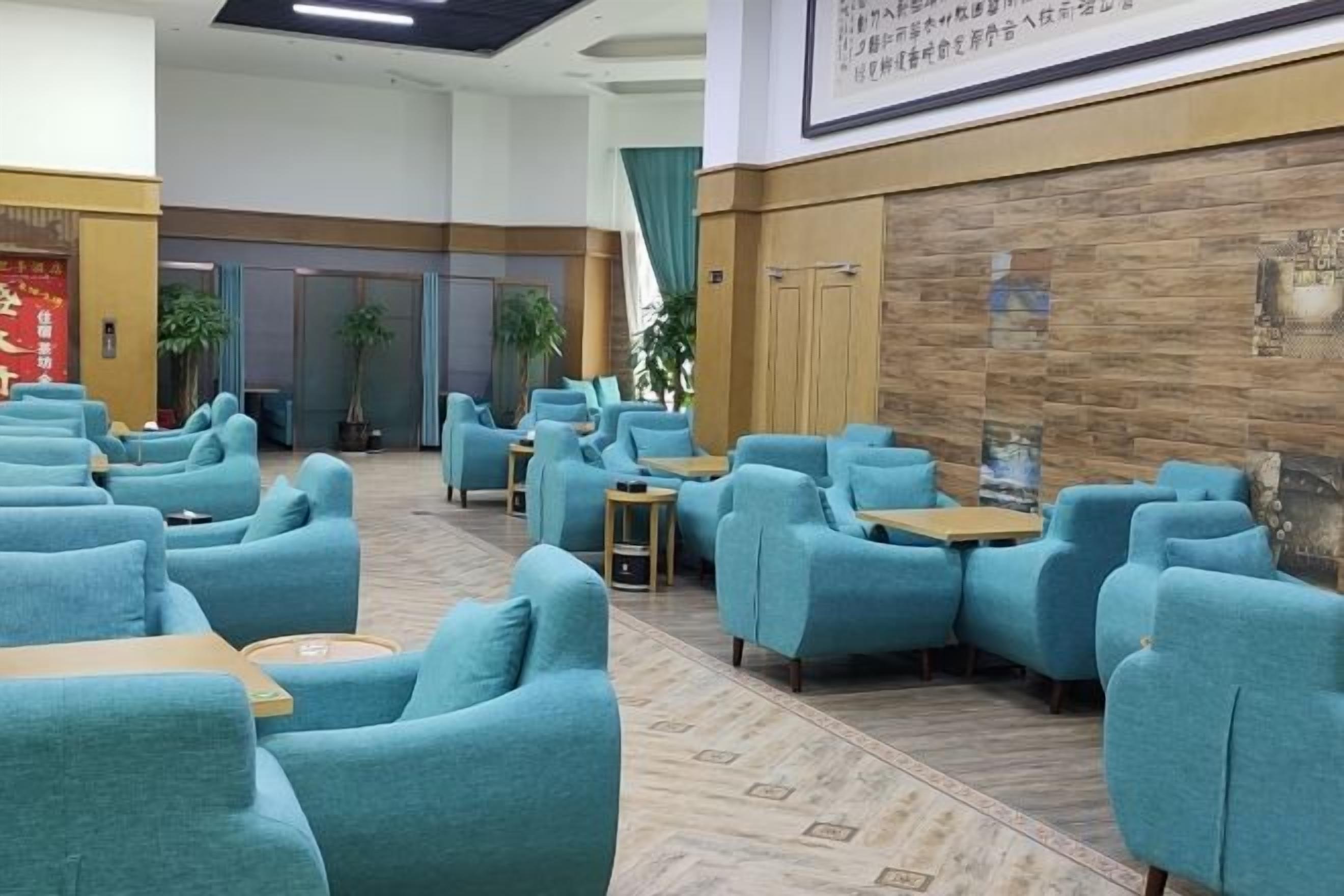 A hotel lobby with seating areas, a reception desk, and a wall with a framed picture.