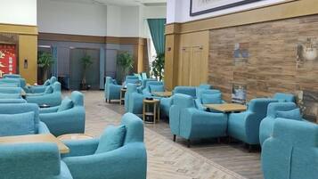 A hotel lobby with seating areas, a reception desk, and a wall with a framed picture.