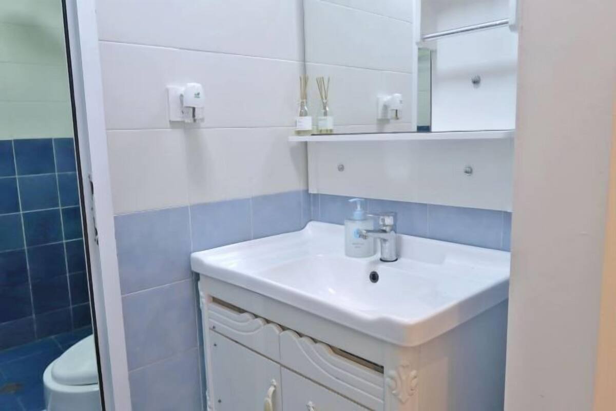 A bathroom with a white sink, mirror, and blue-tiled walls.