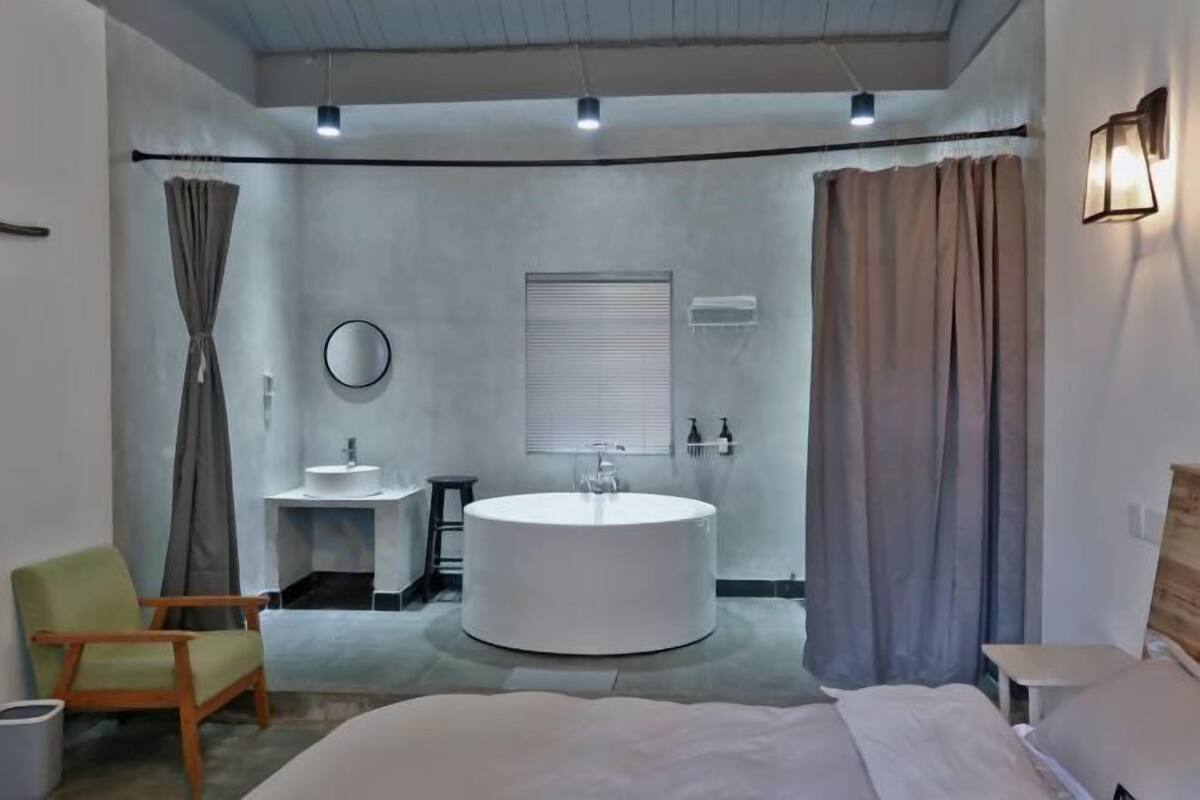A modern bathroom with a round bathtub, a sink, and a mirror.