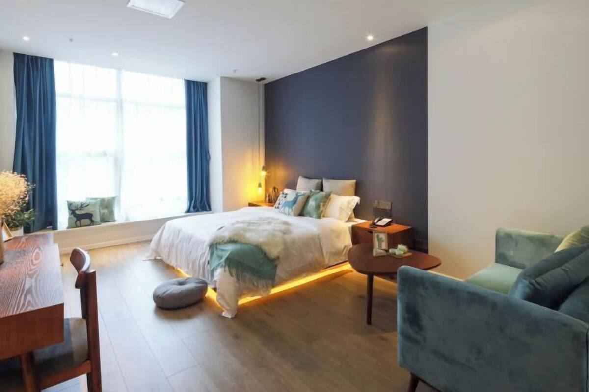 A modern bedroom with a bed, bedside table, and a seating area with a chair and sofa.