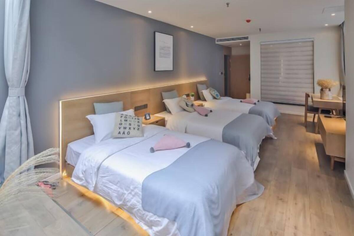 A hotel room with two beds, a desk, and a chair.