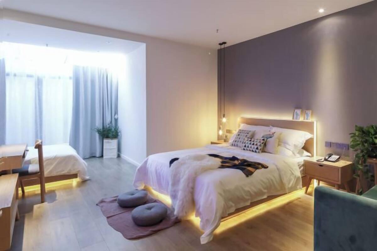 A modern bedroom with a large bed, bedside tables, a desk, and a chair.