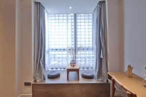 A room with a large window, a small table, and two cushions on a bench. - Yi She (Chongqing)