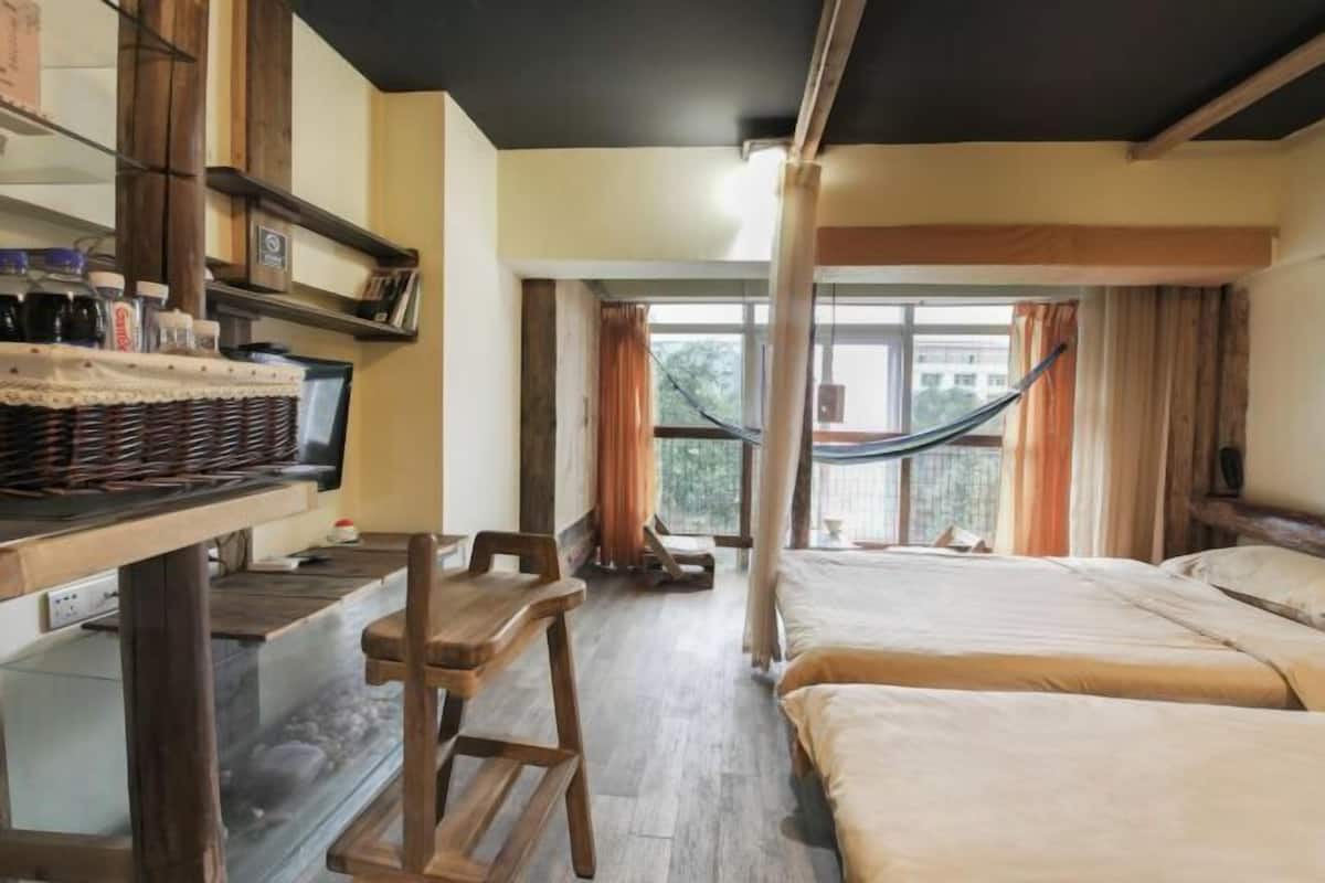 A room with two beds, a wooden desk, a fish tank, and a hammock.