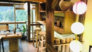 A rustic interior with wooden furniture, a dining area, and a view of greenery outside. - Linmusen Hostel (Chongqing Beibei Pedestrian Street Center) (Chongqing)