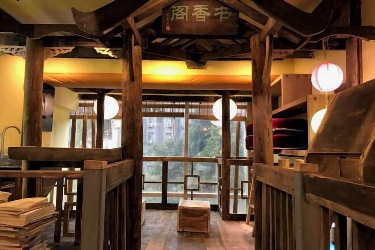 A traditional Japanese room with tatami flooring, wooden furniture, and a view through large windows.