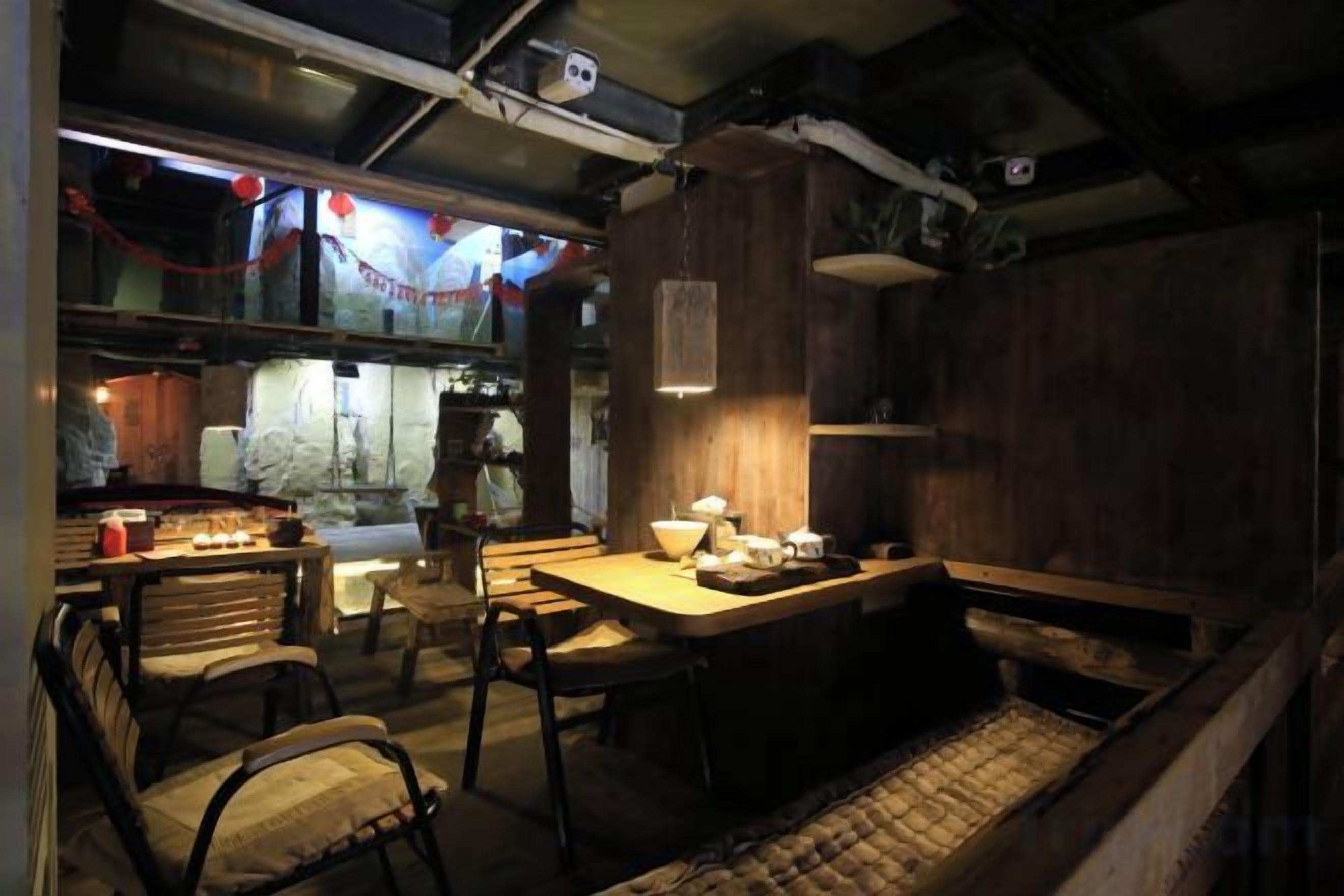 A dimly lit room with a wooden table, chairs, and a bench.