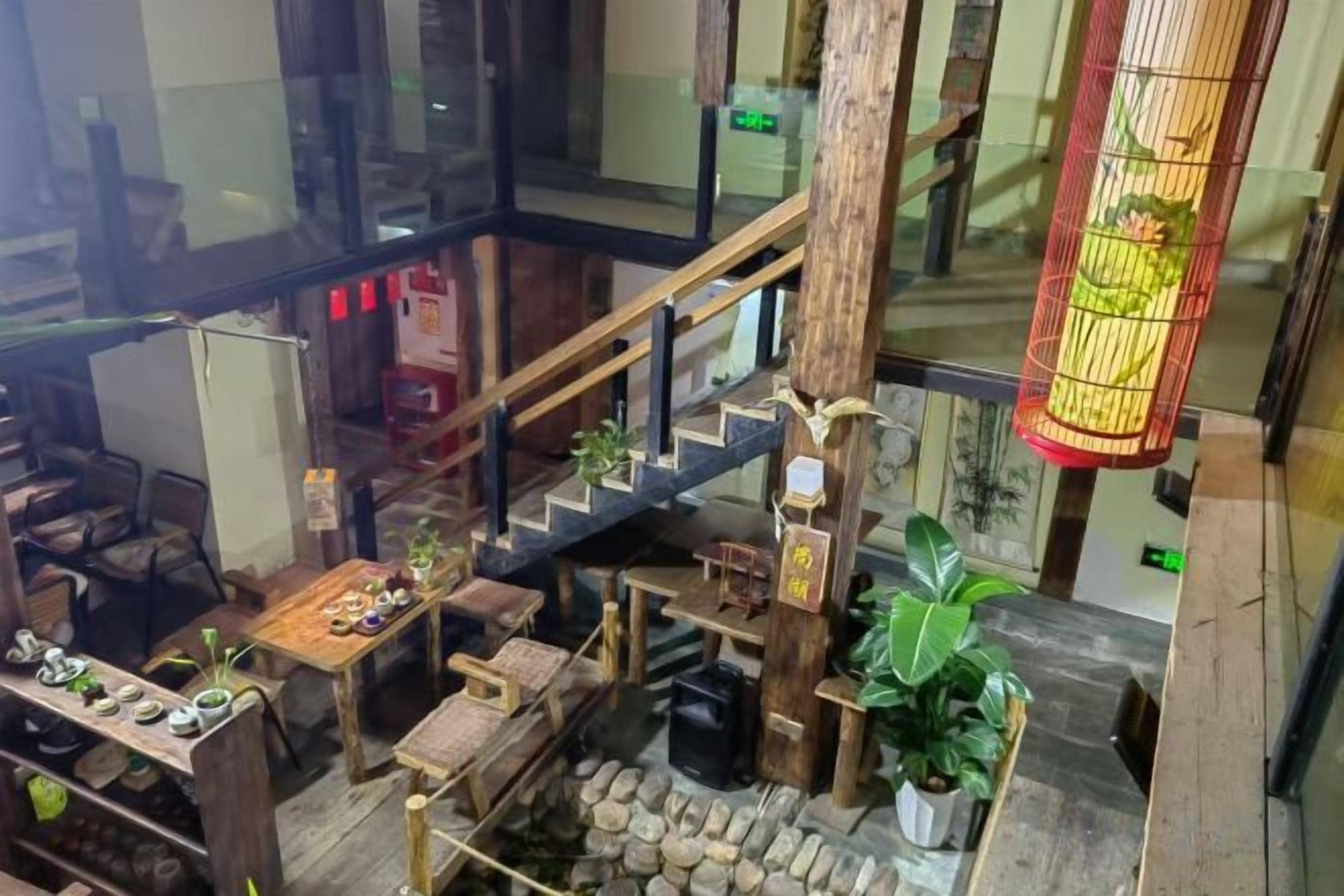 Un interior de varios niveles con una escalera, muebles de madera y plantas en macetas.
