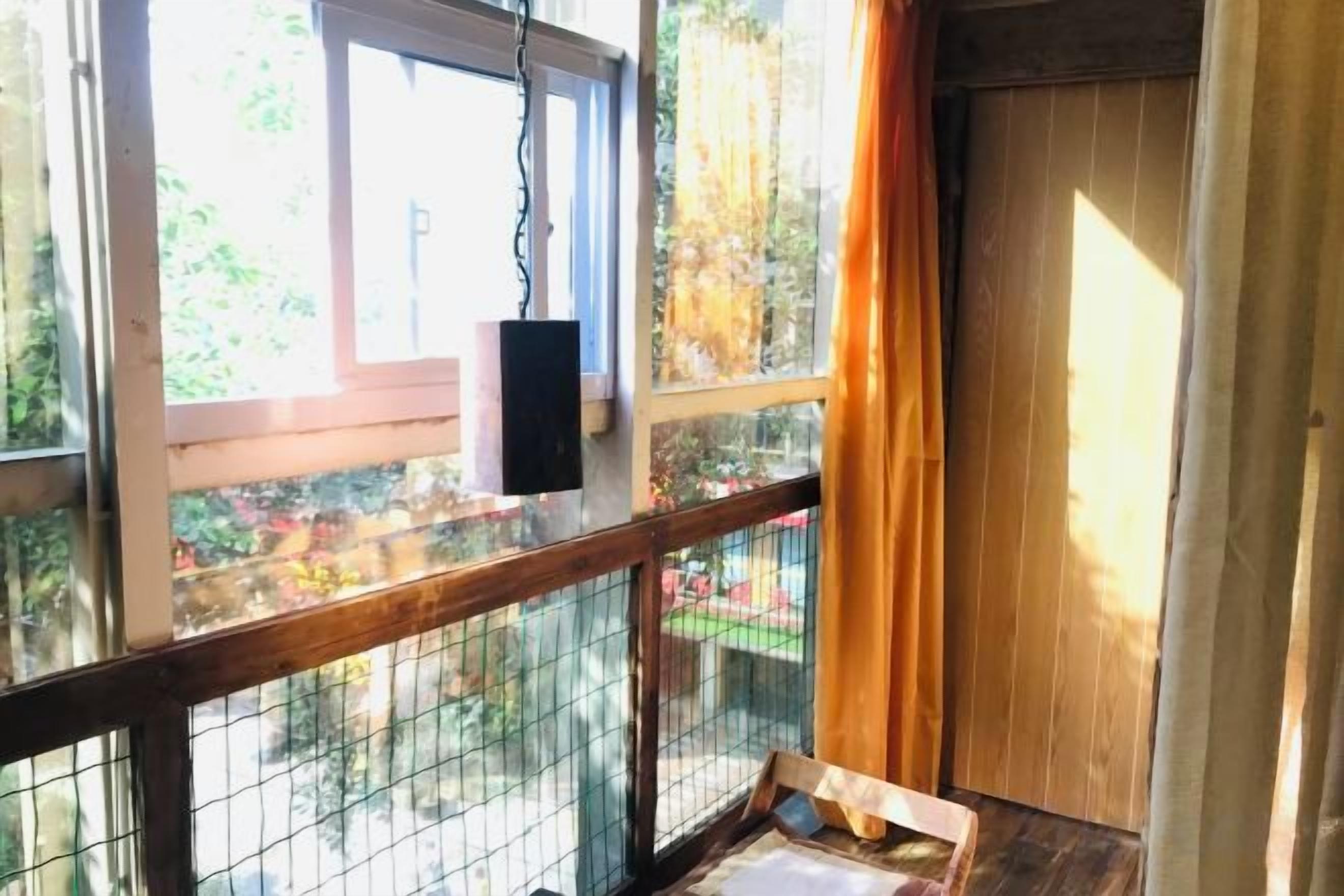 Una habitación con baranda de madera, comedero colgante para pájaros y vistas al exterior.