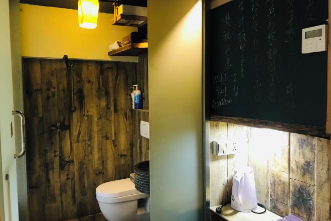 Un baño con pared de madera, inodoro, lavamanos y espejo.
