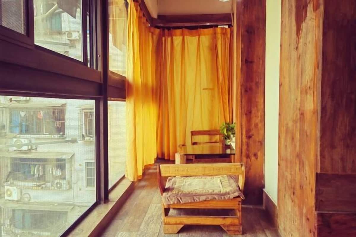 A room with a wooden bench, a window with yellow curtains, and a view of buildings outside.