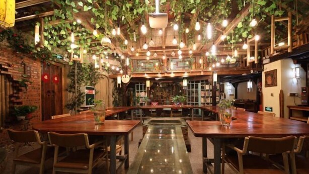 An indoor dining area with wooden tables and chairs, hanging plants, and pendant lighting. - Linmusen Hostel (Chongqing Beibei Pedestrian Street Center) (Chongqing)