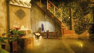 Un interior tradicional con una pared de piedra, una escalera de madera y un banco.