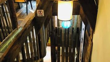 A wooden staircase with a handrail, a light fixture, and a no-smoking sign.