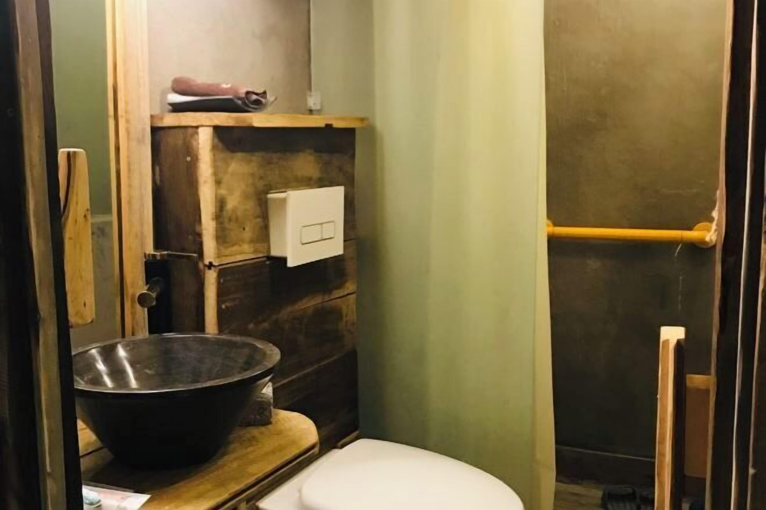 Pieni kylpyhuone, jossa on puinen allaskaappi, valkoinen wc-istuin ja suuri pesuallas.