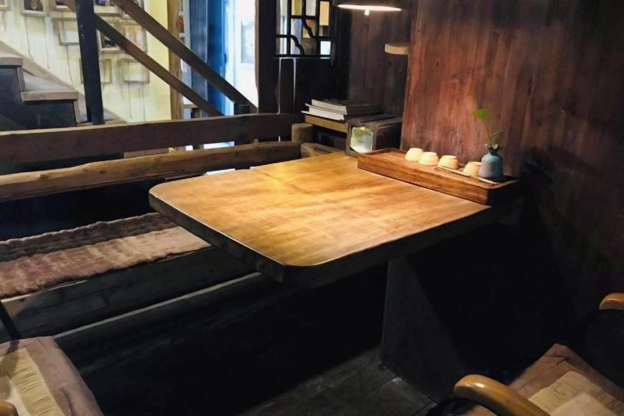 A wooden bench with a table, a small plant, and a staircase in the background.