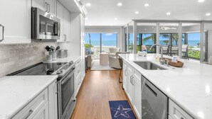 Una cocina moderna con armarios blancos, electrodomésticos de acero inoxidable y vistas al océano.