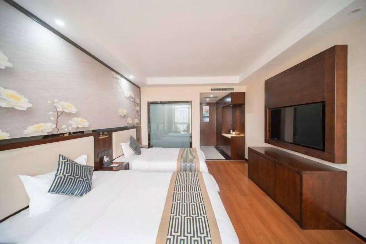 Une chambre d’hôtel moderne avec un grand lit, une télévision et un mur décoratif en bois.