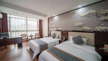 Habitación de hotel con dos camas, un escritorio, una silla y un ventanal grande.